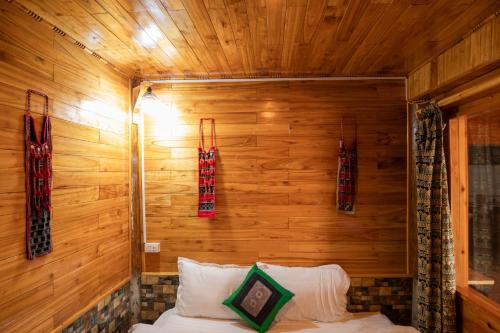 a bedroom with a wooden wall with a bed in it at Hmong Farmstay in Sa Pa
