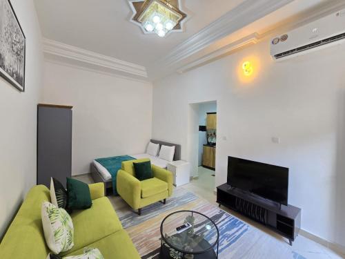 a living room with a green couch and a television at Fully furnished studio on Ground floor in Abu Dhabi
