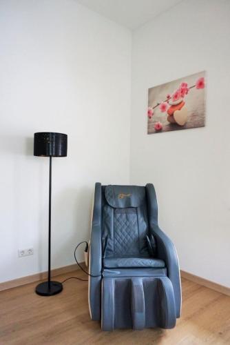 a blue reclining chair in a room with a lamp at Ferienwohnung AUSZEIT Ottobeuren in Ottobeuren