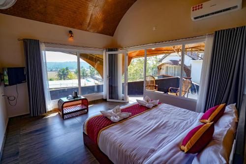 a bedroom with a large bed with large windows at Ginberry Holidays in Wayanad