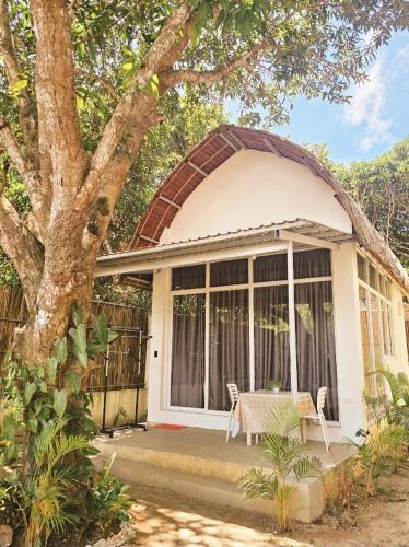 a small white house with a table and chairs at Lio Palm Villas in Langi-langiban