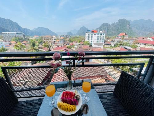 a table with a bowl of fruit and drinks on a balcony at VANG VIENG TOPVIEW HOTEL in Vang Vieng