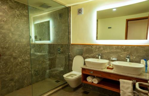a bathroom with a sink and a toilet and a mirror at White Sands Hotel in Dar es Salaam