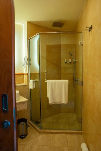 a bathroom with a glass shower with a towel at White Sands Hotel in Dar es Salaam