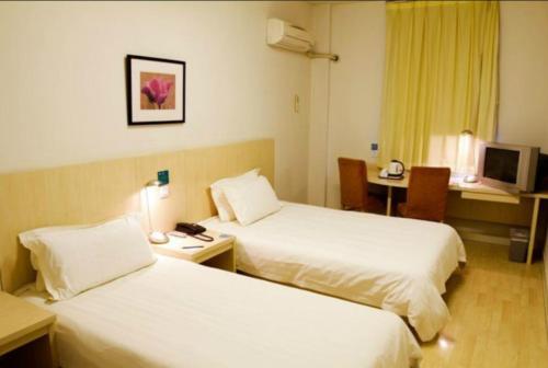 a hotel room with two beds and a desk at Jinjiang Inn Shenyang North Railway Station Huigong Square in Shenyang