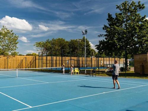 trois personnes jouant au tennis sur un court de tennis dans l'établissement Mobil home camping La Réserve , Gastes 40160, à Gastes