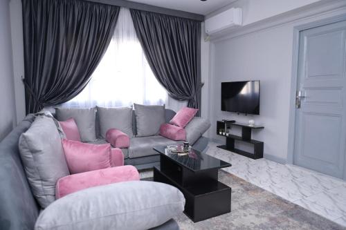 a living room with a grey couch and pink furniture at Belle Helen - Bright Independent Apartment in Cairo