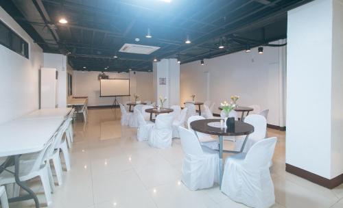 a conference room with tables and white chairs and a screen at RedDoorz at Nucell in Cebu City