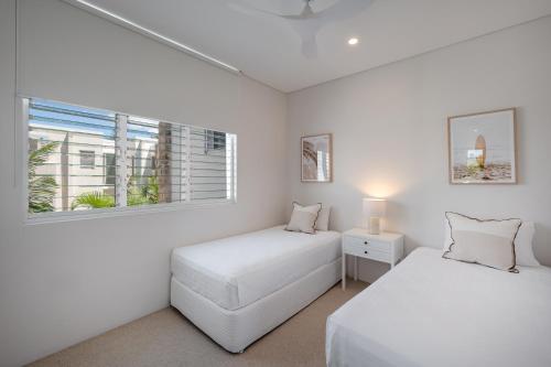 two beds in a white room with a window at Luxury Riverside Escape in Noosaville