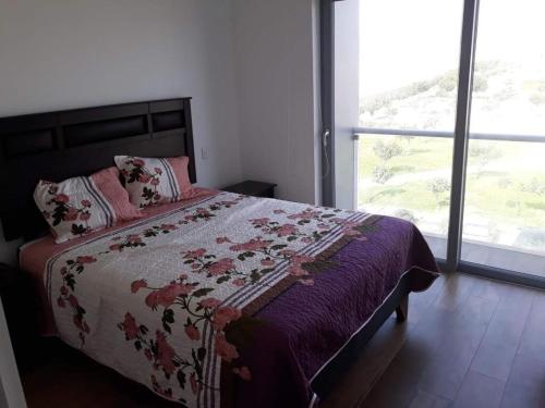 een slaapkamer met een bed met een bloemenbed en een raam bij Apartment Rosi Beach & Pool Punta Hermosa in Punta Hermosa