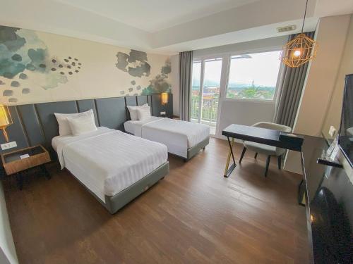 a hotel room with two beds and a desk at Nemuru Grand Bhuvana Ciawi in Bogor