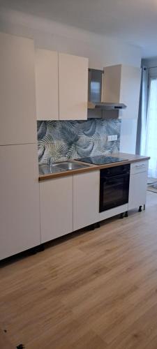 une cuisine avec des armoires blanches et un four à plaques de cuisson dans l'établissement Agréable et frais au Nord joli studio Sophie rénové wifi parking balcon, à Amélie-les-Bains-Palalda