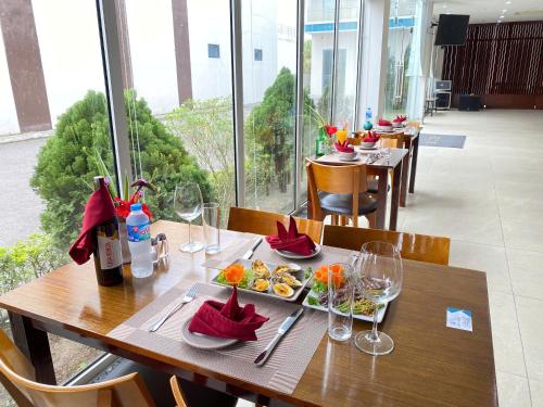 a wooden table with plates of food and wine glasses at Juna hotel in Thanh Hóa