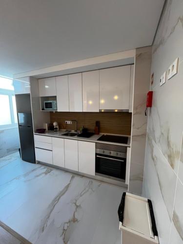 a kitchen with white cabinets and a marble floor at Alojamento Casa do Frade in Cabeço de Alhos Vedros