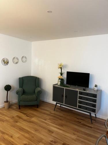 a living room with a tv and a green chair at Alojamento Casa do Frade in Cabeço de Alhos Vedros