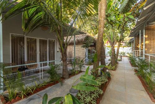 a courtyard with palm trees and a house at Royal Touch Beach Huts in Palolem