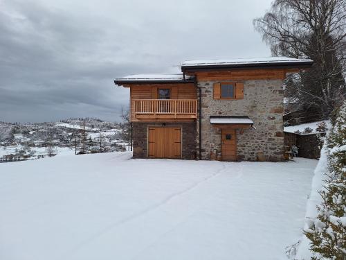 a log cabin in the snow with a snow covered yard at Mas dei Candidi in Baselga di Pinè