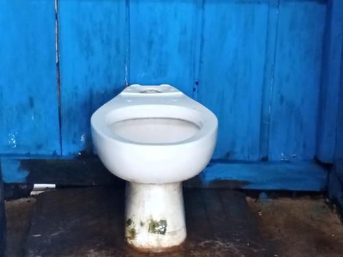 - des toilettes blanches situées en face d'un mur bleu dans l'établissement Warfanin Homestay, à Pulau Gam