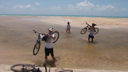 a group of people holding their bikes on the beach at Dolphin B&B Pousada Gasthaus in Maragogi