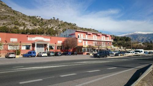 una calle con coches estacionados frente a un edificio en Hostal Restaurante el cruce, en El Padul