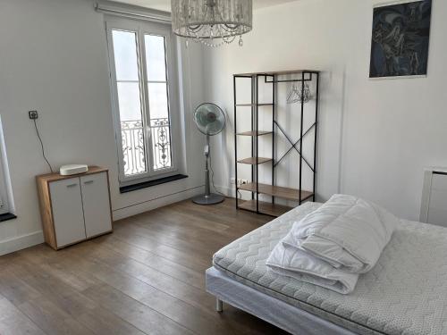 una camera con letto, ventilatore e finestre di Grand duplex centre historique a La Rochelle
