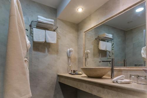 a bathroom with a sink and a large mirror at Galilion Hotel in Yesod Hamaala