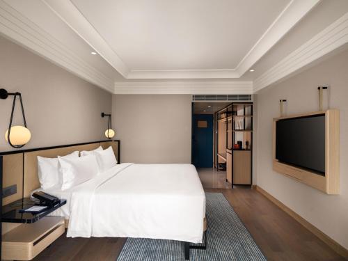 a bedroom with a white bed and a flat screen tv at Pullman Chennai Anna Salai - Premium Brand By Accor in Chennai