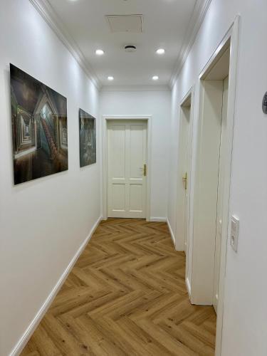 a hallway with white walls and wood floors and paintings at morand I Apartments in Salzburg