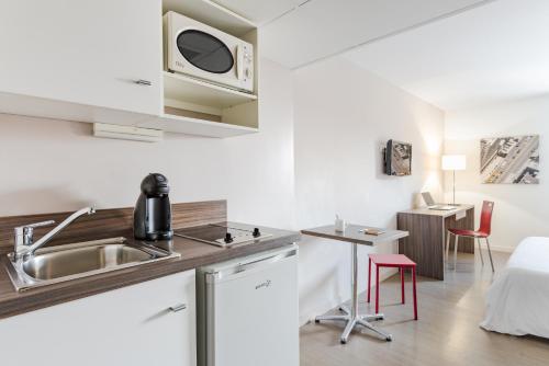 a kitchen with a sink and a microwave at Appart’hôtel Hevea in Valence