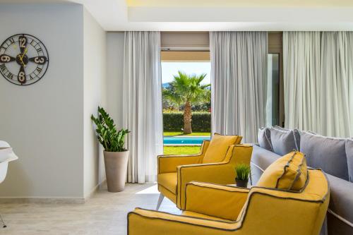 a living room with yellow chairs and a couch at Aria Villas - Private Pool, Playground, Ping Pong & Close to Beach, By ThinkVilla in Pigi