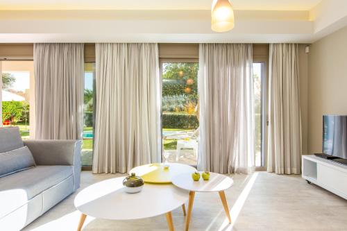 a living room with a couch and a table at Aria Villas - Private Pool, Playground, Ping Pong & Close to Beach, By ThinkVilla in Pigi