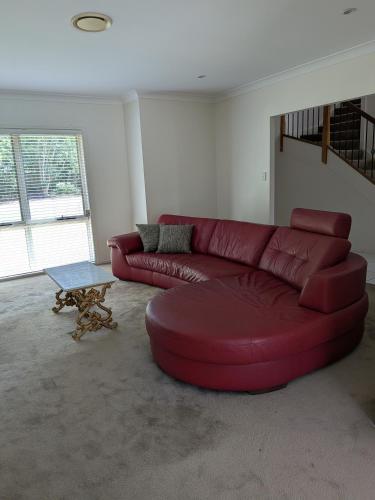 a red leather couch in a living room at Modern Home - 10 Guests - 5 Bedrooms and Pool in Bundamba