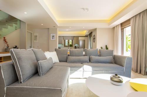 a living room with a couch and a table at Aria Villas - Private Pool, Playground, Ping Pong & Close to Beach, By ThinkVilla in Pigi