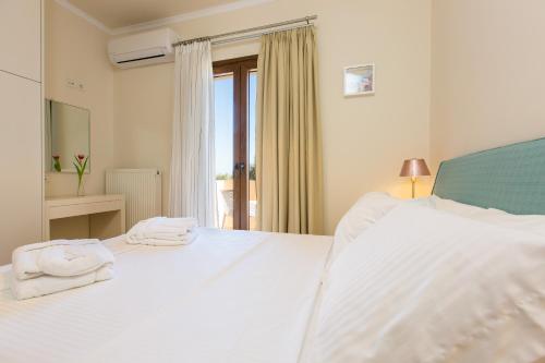 a bedroom with a white bed with towels on it at Aria Villas - Private Pool, Playground, Ping Pong & Close to Beach, By ThinkVilla in Pigi