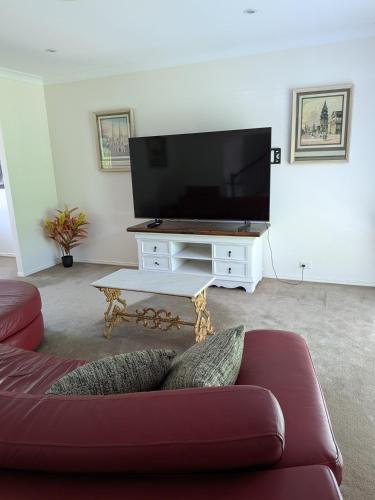 a living room with a couch and a flat screen tv at Modern Home - 10 Guests - 5 Bedrooms and Pool in Bundamba