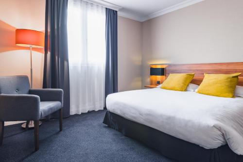 a hotel room with a bed and a chair at Best Western Hotel Atrium Valence in Valence