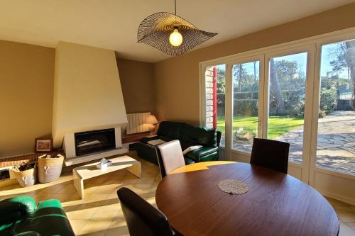 un salon avec une table et des chaises et une cheminée dans l'établissement Maison F5 avec jardin à La Teste-de-Buch, à La Teste-de-Buch