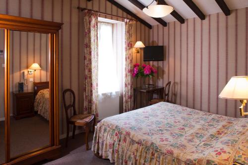 1 dormitorio con cama, ventana y espejo en Hôtel Le Commerce en Mirepoix