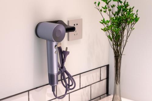 a blow dryer on a counter next to a vase of flowers at Pagoda Hotel Shenzhen Familytrip&BusinessTravel in Shenzhen
