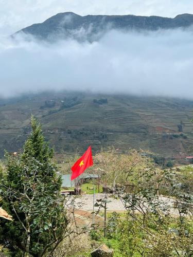 a red flag on top of a mountain with clouds at Táo Tày House in Sa Pa