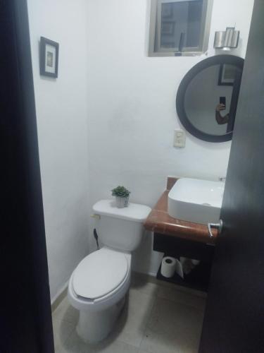 a bathroom with a toilet and a sink and a mirror at Cancun in Cancún