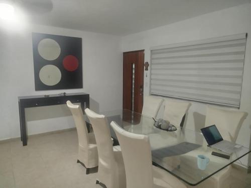 a dining room with a glass table and chairs and a laptop at Cancun in Cancún