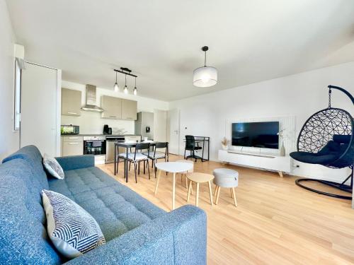 un salon avec un canapé bleu et une cuisine dans l'établissement ParcAppart 5 - Terrasse - Parking - Netflix, à Lanester