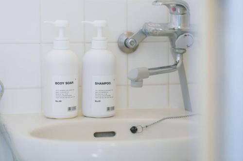 a bathroom sink with two bottles of soap and a faucet at 5B Guest House INFINITY in Naha