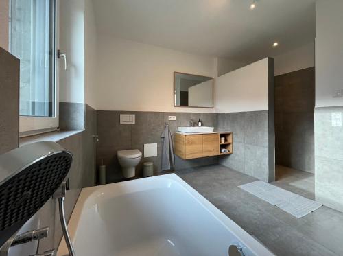 a bathroom with a tub and a toilet and a sink at Ferienhaus Laurentius für 12 Personen in Ohlstadt in Ohlstadt