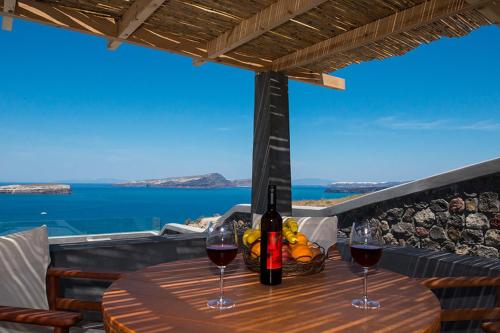a table with two glasses of wine on a balcony at Our Villa Santorini in Akrotiri