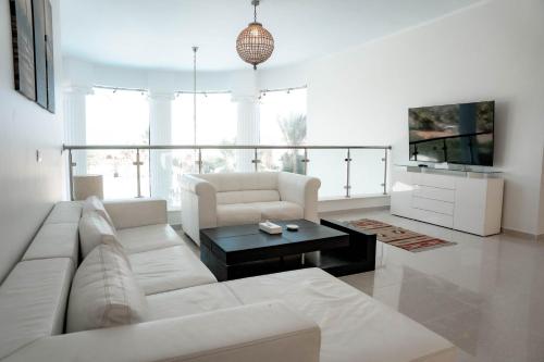 Caves Beach Resort Adults Only في الغردقة: غرفة معيشة مع أريكة بيضاء وتلفزيون
