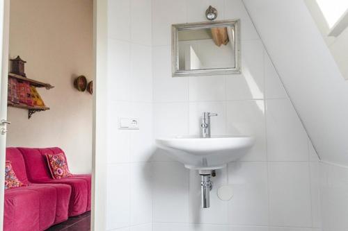 a bathroom with a sink and a red couch at B&B de Remketting in Slijk-Ewijk