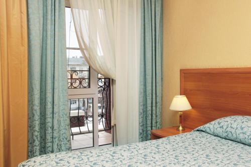 ペレスラヴリ・ザレスキーにあるPereslavl Hotelのベッドルーム1室(ベッド1台付)、窓、バルコニーが備わります。