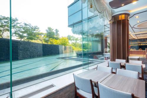 a dining room with a pool and a table and chairs at Hotel Springs Makuhari Premier in Chiba